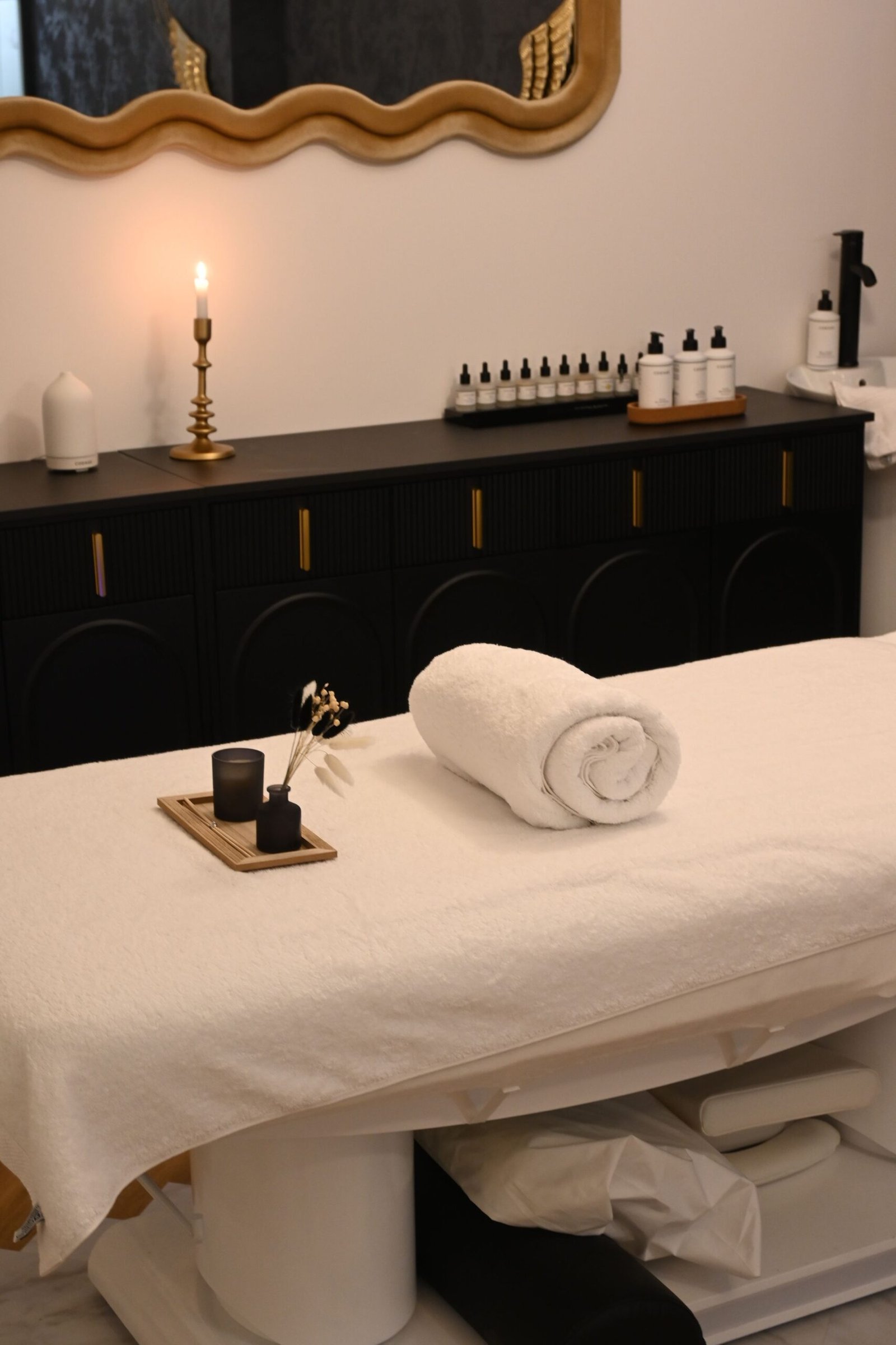Softly lit treatment room with candle, natural oils and rolled linen at Buddha Spa