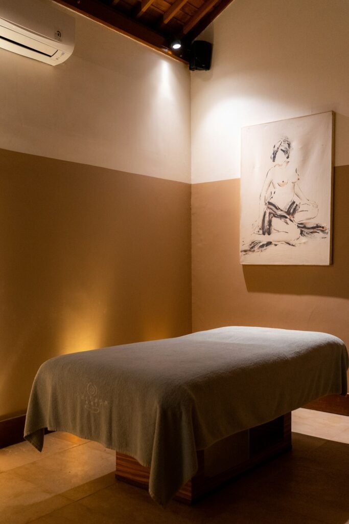 Warm-lit spa treatment room with a single treatment bed and soft ambient lighting