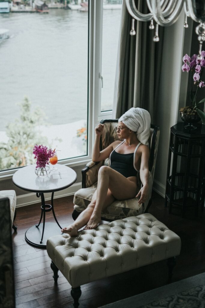 Woman in robe with towel wrap relaxing by a window with flowers