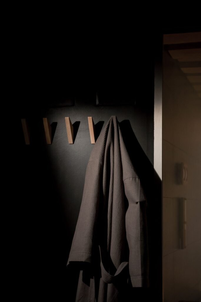 A robe hanging on wooden pegs in a dim, softly lit spa corridor