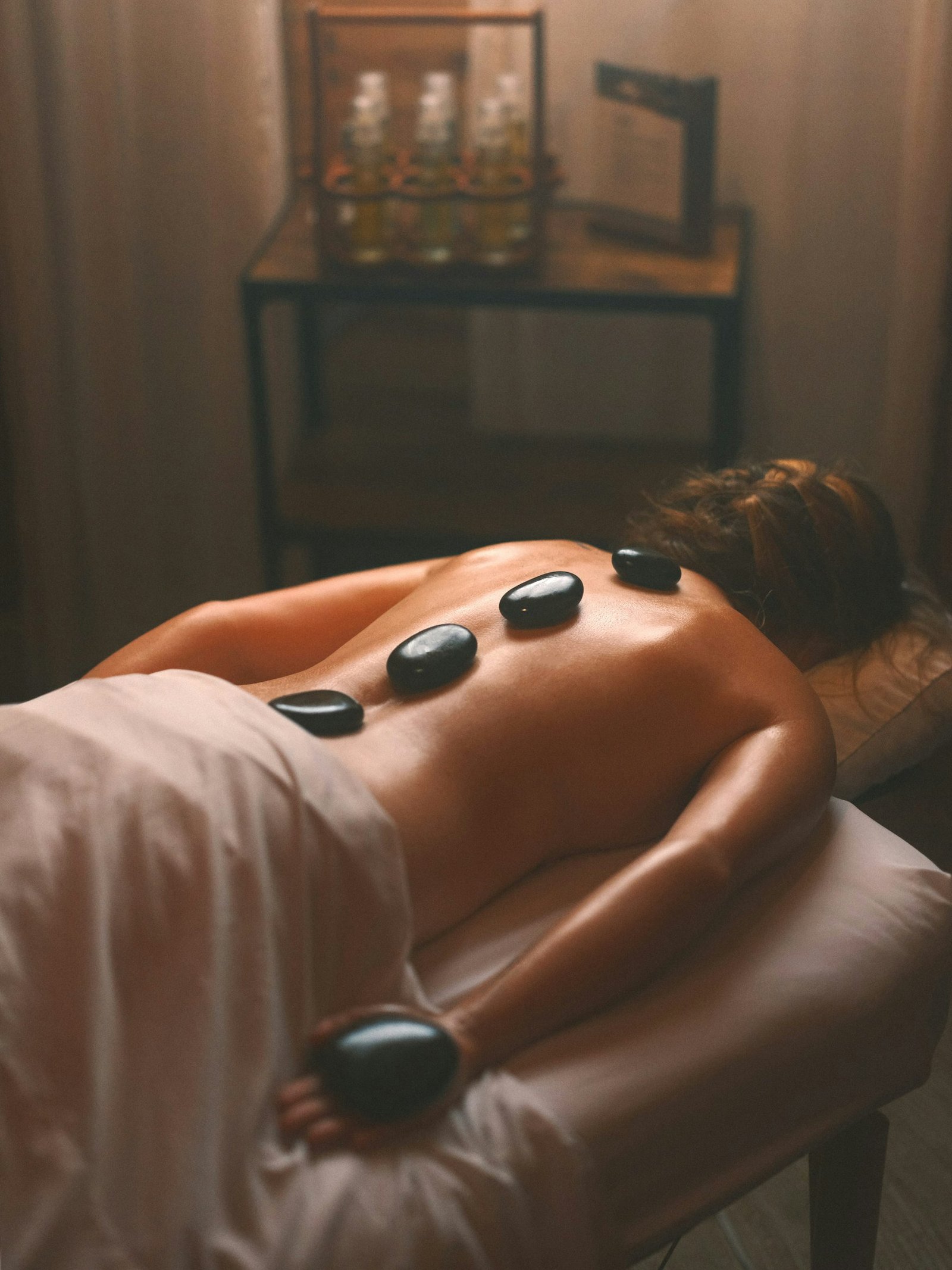 Smooth black hot stones placed along a person's back in a warm treatment room