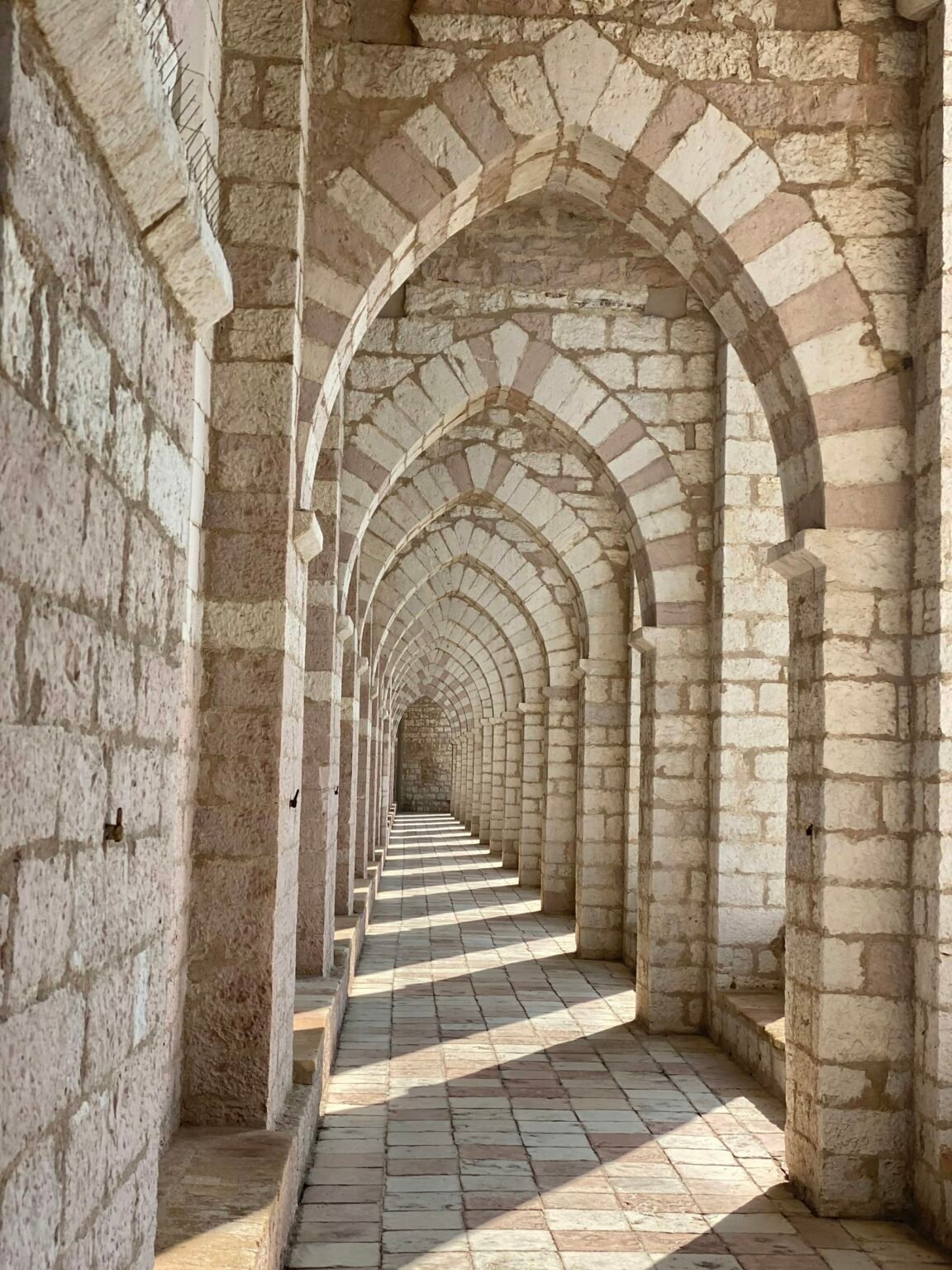 A sandstone arched corridor in Jaipur with afternoon light falling across the stone floor