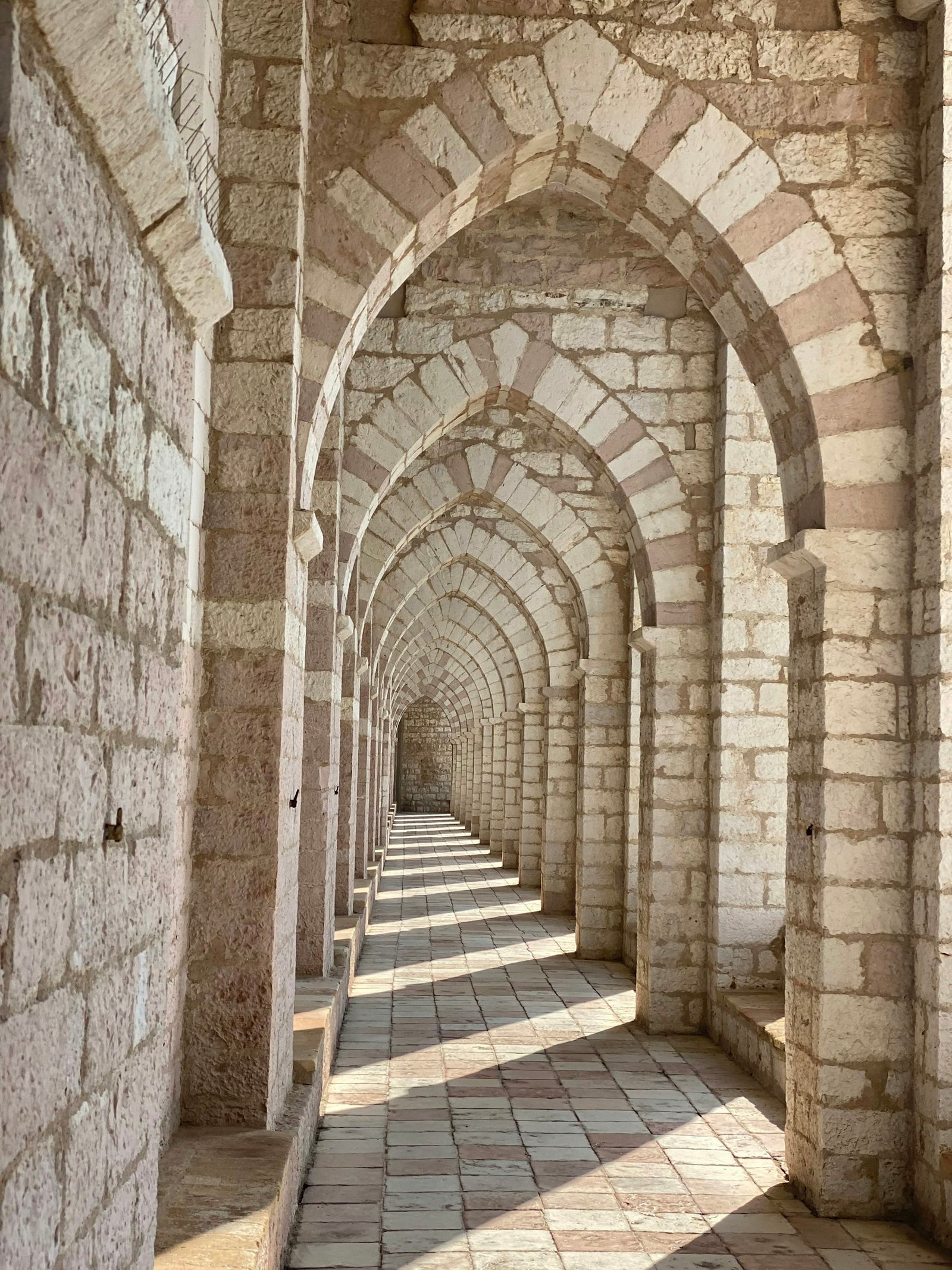 Sandstone arched corridor with warm weathered plaster texture