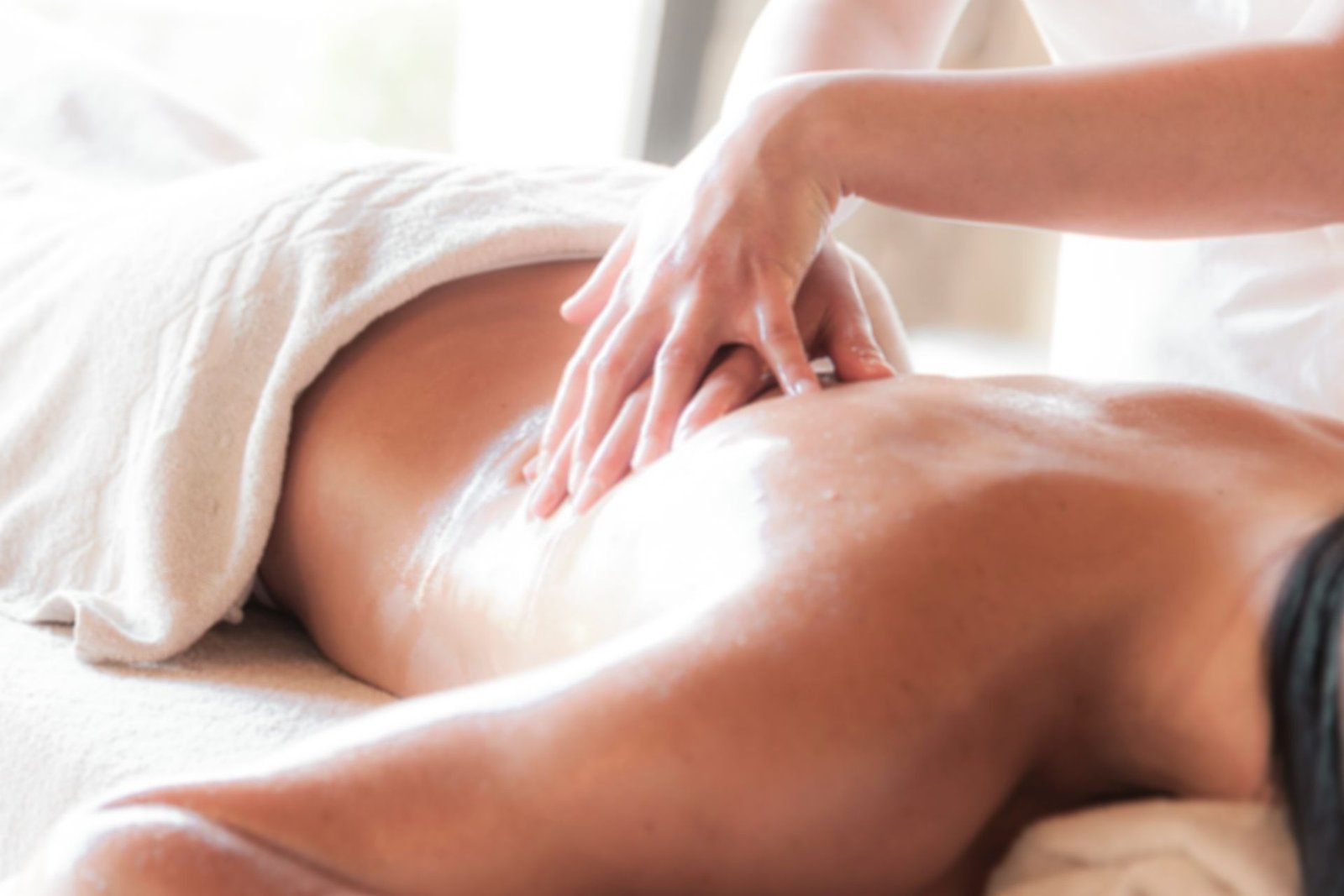 Therapist giving a relaxing full body back massage in a soft-lit spa setting