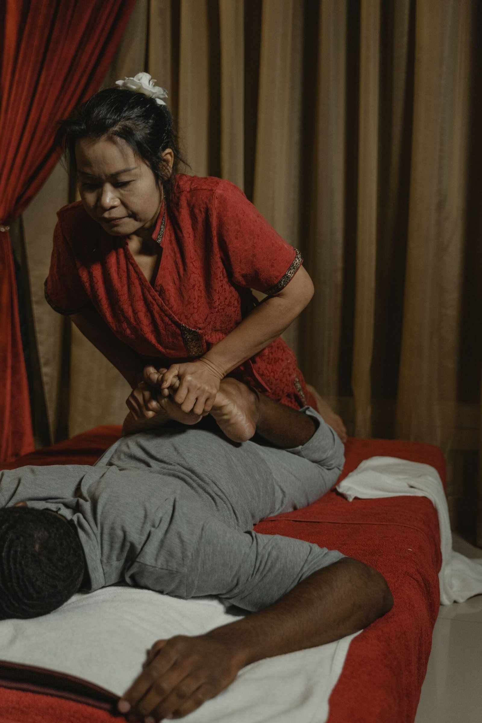 Therapist performing traditional Thai therapy assisted foot and leg stretch